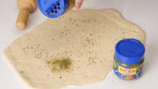 Mezclar los ingredientes para formar la masa. Estirarla y darle forma redonda. Espolvorearla con Avecrem Caldo de Pollo Granulado y condimento de finas hierbas.