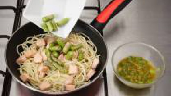 Saltea los espaguetis con un poco de aceite, añade el salmón y las puntas de los espárragos