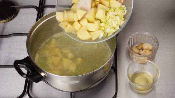 Pela las patatas y córtalas en trozos no muy pequeños. Añade las patatas y la parte blanca de los puerros al caldo hirviendo. Por último, añade también el aceite de dorar los ajos, frío y colado.