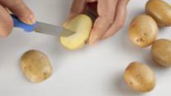 Pela las patatas y pártelas por la mitad. Realiza unos cortes finos con un cuchillo en cada una de las mitades y añade el aceite de oliva.