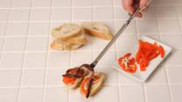 Coloca sobre el pan las tiras de pimiento y adorna estas con las anchoas. Sirve.