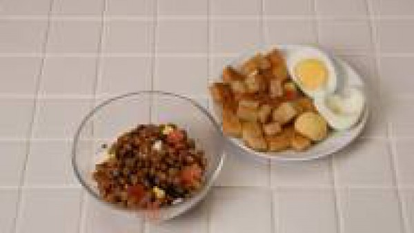 Mezcla las lentejas con el queso, el tomate y el huevo duro. Alíñalo con la vinagreta y sírvalo con pan frito cortado en dados.