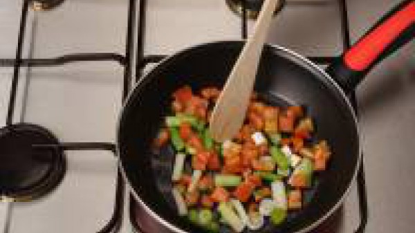 Fríe los ajos tiernos en el aceite caliente y añade el arroz, deja que se dore ligeramente. Añade el tomate frito.