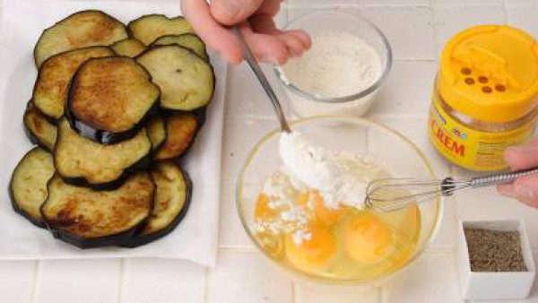 Corta las berenjenas a rodajas gruesas y fríelas. Réservalas sobre papel de cocina. Bate los huevos junto con la harina y sazonálos con Avecrem Caldo de Pollo y pimienta.