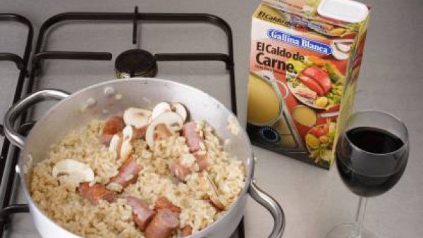 Calienta una cucharada de mantequilla con un poco de aceite en una cazuela de fondo grueso. Fríe las salchichas cortadas. Añade los ajos picados y la cebolla troceada. Deja dorar. Agrega las setas (pr