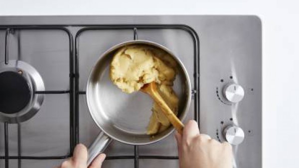 Mezcla con una cuchara de madera hasta obtener una pasta fina. Continúa removiendo hasta que la pasta se desprenda del cazo unos 3 minutos. Deja enfriar a temperatura ambiente unos 10 minutos. Añade l