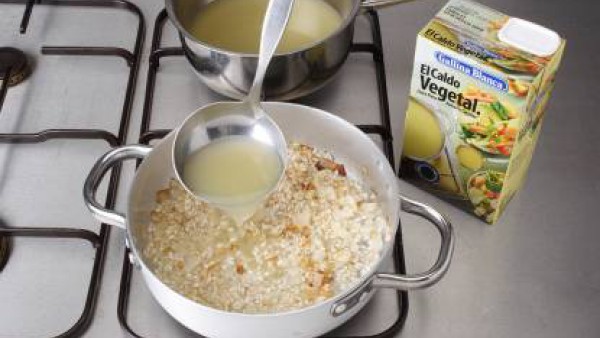 Calienta la mantequilla en una cazuela y rehoga el sofrito de cebolla, añade el ajo picado y deja dorar. Agrega el arroz y dóralo sin dejar de remover. Vierte un vaso del caldo y cuece el arroz durant