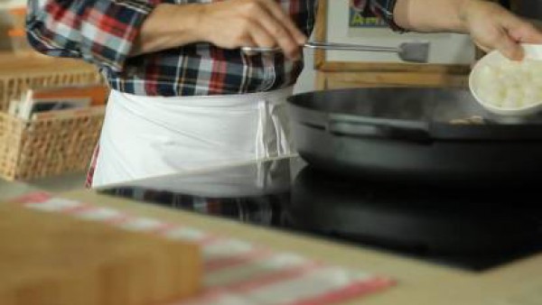En la misma cazuela pocha ligeramente la cebolla picada gruesa, el ajo picado y el bacón cortado en dados. Lava y corta la parte terrosa de los champiñones. Corta en cuartos e incorpora al guiso, pros