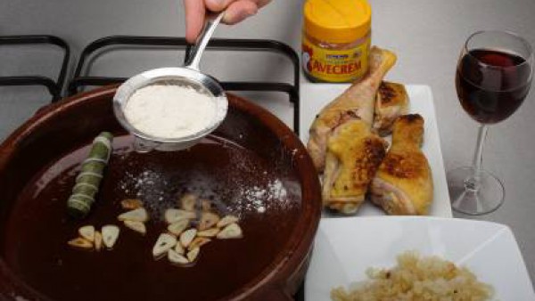 En una cazuela calienta aceite y dora los trozos de pollo, reservándolos. En la misma grasa, añade los ajos a láminas. Espolvorea con un poco de harina, rocía con el vino y agrega los trozos de pollo 