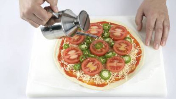Echa una pizca de sal, una pizca de orégano y un buen chorrito de aceite de oliva por encima de toda la superficie de la pizza.