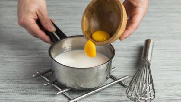 Reserva una cucharada de leche y calienta el resto, junto con el azúcar, la rama de canela y la piel de limón, hasta que hierva. En un bol, mezcla las yemas y el almidón. Cuando la leche hierva, échal
