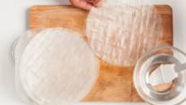 Prepara las hojas de arroz bañándolas con agua. Así conseguirás que sean mas suaves y fáciles de trabajar.  Llenar cada hoja con verduras y una cucharada de Tomate Frito Gallina Blanca. Después ciérra