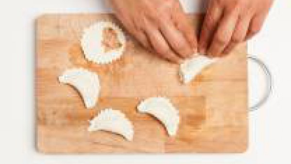 Después de haber cepillado de los bordes de los discos de masa con la leche, rellena los círculos de hojaldre con el atún y el tomate frito. Finalmente, dobla los discos formando medias lunas, presion