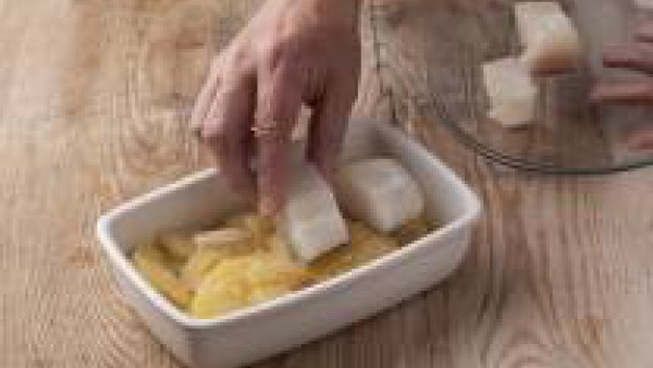 Añade el bacalao cortado encima de las patatas y cuece unos 7 minutos más en el horno, hasta que el bacalao y las patatas estén cocinados.