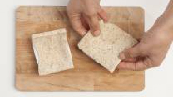 Con un rodillo, aplastar finas rebanadas de pan integral de sándwich