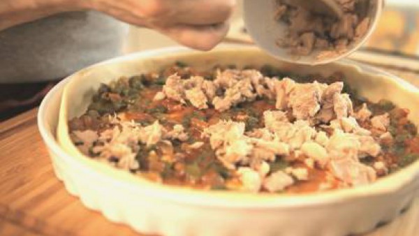 Deja enfriar el sofrito. Pon la mitad de la masa sobre una bandeja de horno, extiende el sofrito y reparte por encima el atún y el huevo duro picado. Debes dejar un margen de un dedo para poder cerrar