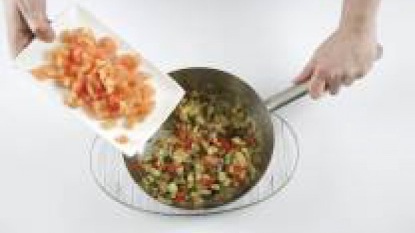 Pela la cebolla y córtala en daditos. Pon en una cacerola 2 cucharadas de aceite de oliva, echa la cebolla y déjala cocer. Añade el pimiento rojo cortado y la berenjena y deja que se cuezan.