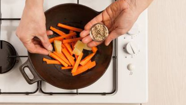 En un wok con un poco de aceite de oliva virgen extra fríe las zanahorias y las patatas con el ajo, agrega las semillas de hinojo y la pastilla de caldo desmenuzada, añade un vaso de agua y cuece dura