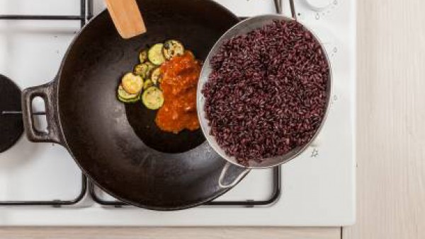 En un wok, saltea el calabacín con 1 cucharada de aceite de oliva. Añade el contenido del tomate frito y mézclalo con la carne picada cocina previamente. Escurre bien el arroz y sazona con la salsa de