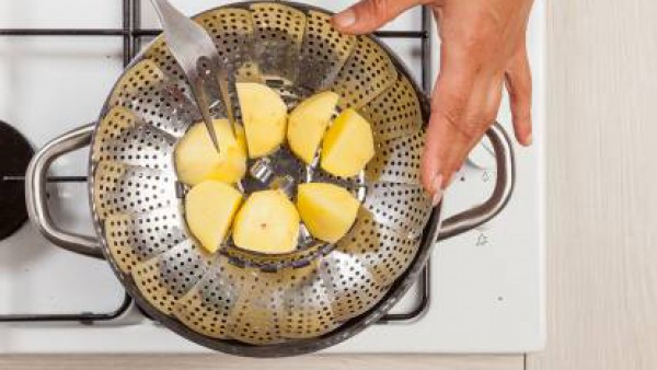 Mientras tanto, pela las patatas y córtalas en trozos no muy pequeños. En una olla para cocer al vapor, cuece las patatas.
