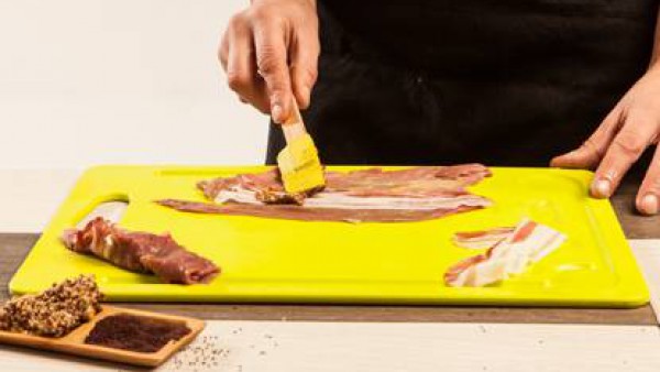 Coloca los filetes de ternera sobre una tabla de cortar y cepíllalos con las semillas de mostaza. Pon sobre cada uno de ellos una loncha de panceta.