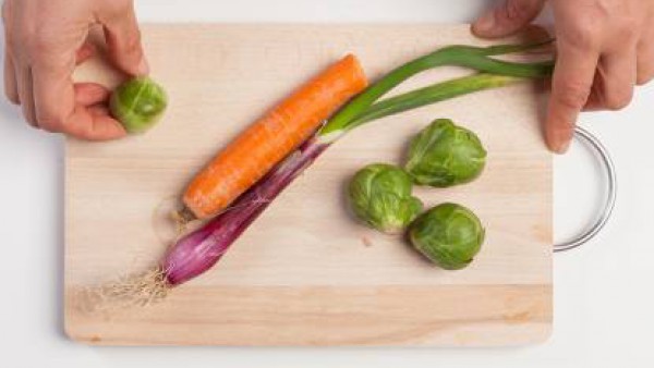 Lava y limpia la verdura, ralla la zanahoria y pica las coles de Bruselas y la cebolla.