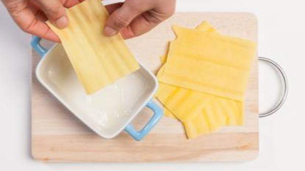 Engrasa ligeramente un molde para hornear, prepara el plato alternando placas de lasaña, bechamel y la mezcla de guisantes. 