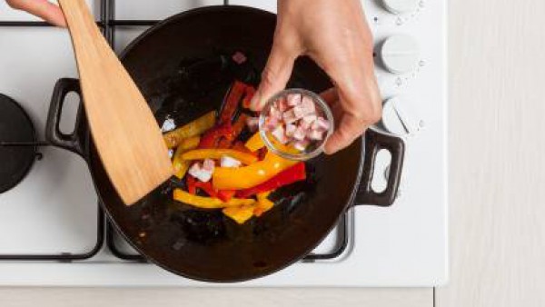 Pon los pimientos en una paella y saltéalos con un poco de aceite y la pastilla de Avecrem Dúo de Tomate. Pasados unos minutos, añade el bacon. 