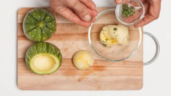 Vacía los calabacines redondos, tritura el interior de los calabacines junto con un diente de ajo y perejil. Añádele el huevo y el pan rallado, mezclar bien y sazona con pimienta.