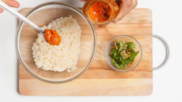 Escurre el arroz y pásalo por agua fría para hacerle perder todo el almidón, añade las aceitunas y albahaca picadas y las cucharadas de sofrito. Rellena los pimientos, unta con aceite, espolvorea con 