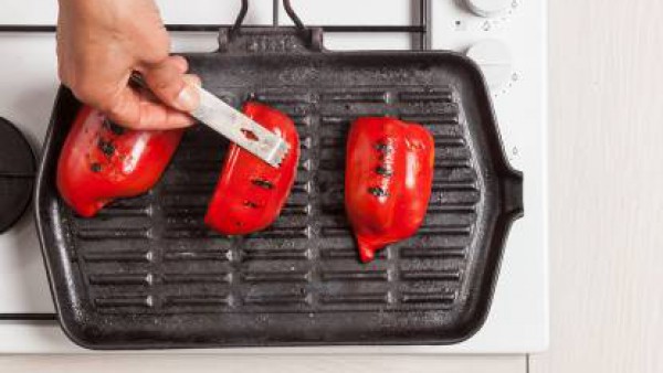 Lava y limpia los pimientos. Asálos en una plancha con un poco de aceite de oliva virgen; a continuación, pélalos y córtalos en tiras.