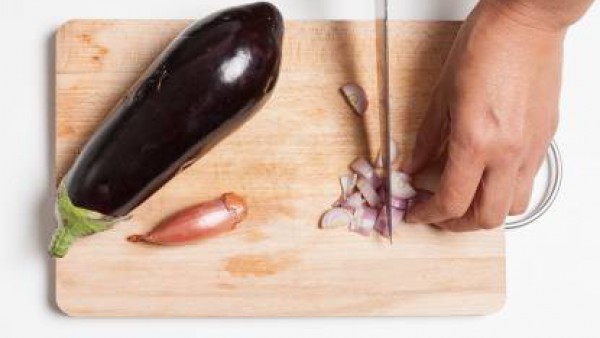 Pela y pica las chalotas. Lava las berenjenas y córtalas en trozos. En un wok, saltea el ajo en el aceite de oliva. Añade las chalotas picadas y las berenjenas.